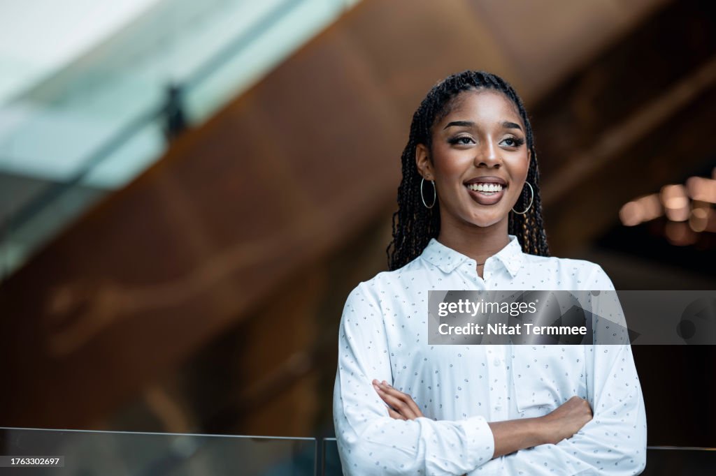 Keeping and Build Up Your Gen Zs Engaged On the Job. Proud of an African-American young businesswoman looking over the shoulder outside of a modern business office.