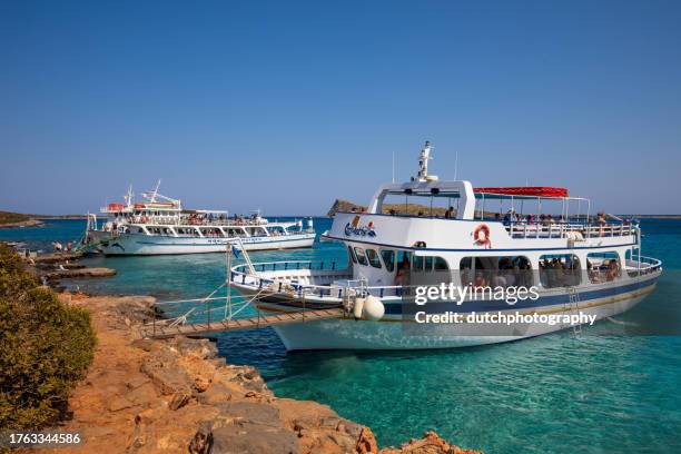 große boote voller touristen, die das klare wasser und die heiße, trockene küste in kolokitha in der nähe von elounda, kreta, erkunden - zonnig stock-fotos und bilder