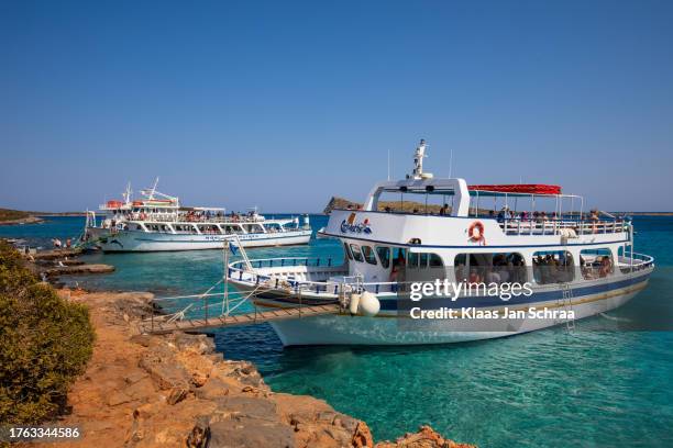 large boats full of tourists exploring the clear waters and hot, dry coastline in kolokitha, near elounda, crete - vakantie strand stock pictures, royalty-free photos & images