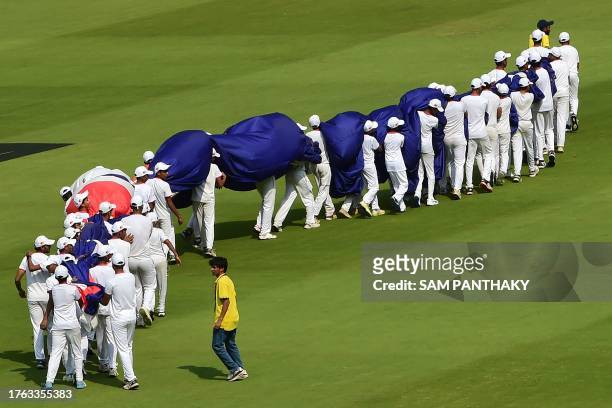 Groundmen carry the national flag of Australia before the start of the 2023 ICC Men's Cricket World Cup one-day international match between England...