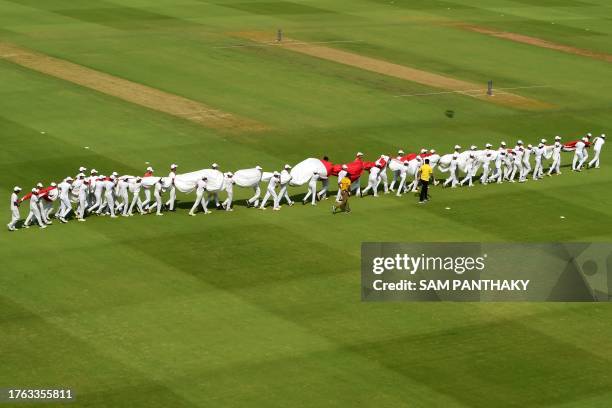 Groundmen carry the national flag of England before the start of the 2023 ICC Men's Cricket World Cup one-day international match between England and...