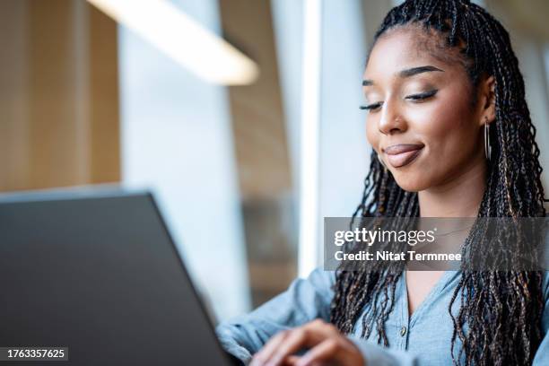 stay connected and engaged from anywhere with hybrid workplace solutions. an african-american businesswoman in a hotel lobby and using her laptop during a business trip. - african hotel stay stock-fotos und bilder