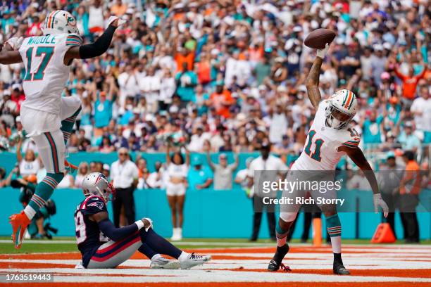 Jaylen Waddle of the Miami Dolphins and Cedrick Wilson Jr. #11 of the Miami Dolphins celebrate while J.C. Jackson of the New England Patriots looks...