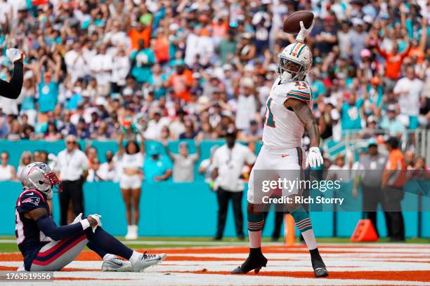 Cedrick Wilson Jr. #11 of the Miami Dolphins celebrates while J.C. Jackson of the New England Patriots looks on after Wilson's receiving touchdown...