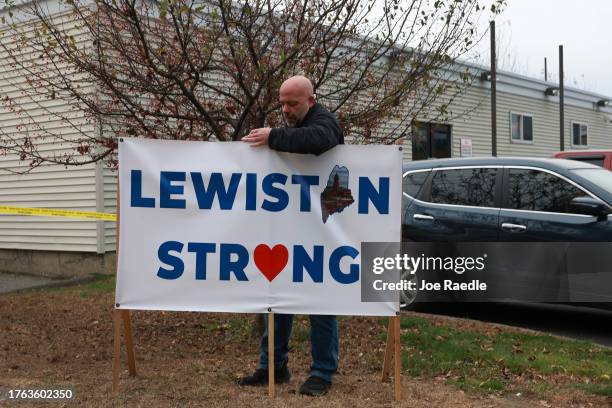 Resident places a Lewiston Strong sign outside of the Schemengees Bar, where one of two mass shootings took place on October 29, 2023 in Lewiston,...