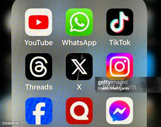 In this photo illustration the logo of US online social media and social networking site 'X' is displayed centrally on a smartphone screen alongside...