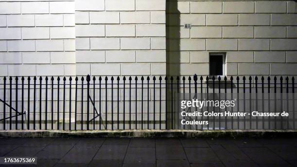 close-up of the white facade of a building with railings and paved sidewalk at night in london, england, united kingdom - asphalt paver stock pictures, royalty-free photos & images