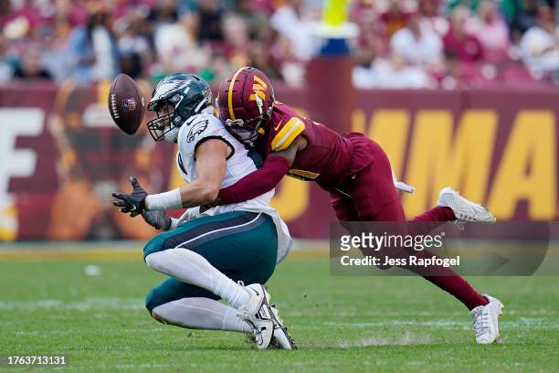 Dallas Goedert of the Philadelphia Eagles eyes the ball as Kamren Curl of the Washington Commanders tackles him in the fourth quarter at FedExField...