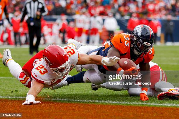 Javonte Williams of the Denver Broncos scores a touchdown as Drue Tranquill of the Kansas City Chiefs defends during the first quarter at Empower...