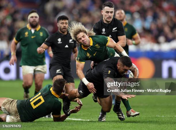 Codie Taylor of New Zealand is tackled by Handre Pollard and Faf de Klerk of South Africa during the Rugby World Cup Final match between New Zealand...