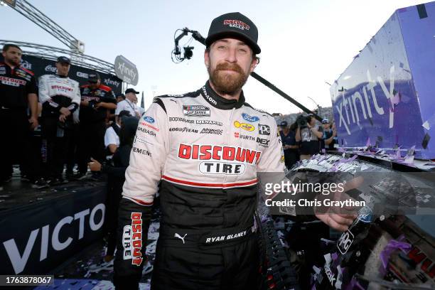 Ryan Blaney, driver of the Discount Tire Ford, poses next to his winner sticker in victory lane after winning the NASCAR Cup Series Xfinity 500 at...