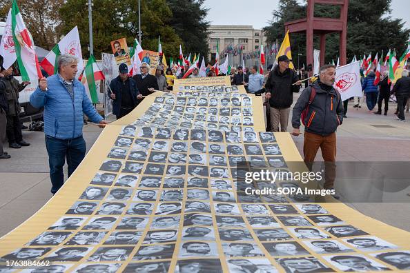 Protesters carry a banner with portraits of the people...