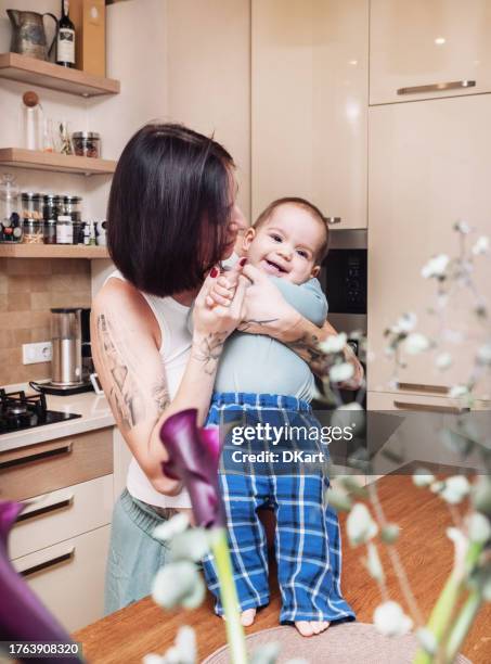 a young pregnant mother dances with her one year old daughter on the kitchen table at home - arab people stock pictures, royalty-free photos & images