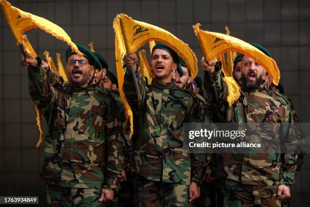 November 2023, Lebanon, Beirut: Pro-Iranian Hezbollah militants chant slogans during the funeral procession of their comrade, who was killed in...