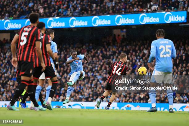 Jeremy Doku of Manchester City shoots and watches the ball bounce off teammate Manuel Akanji of Manchester City to score their 3rd goal during the...