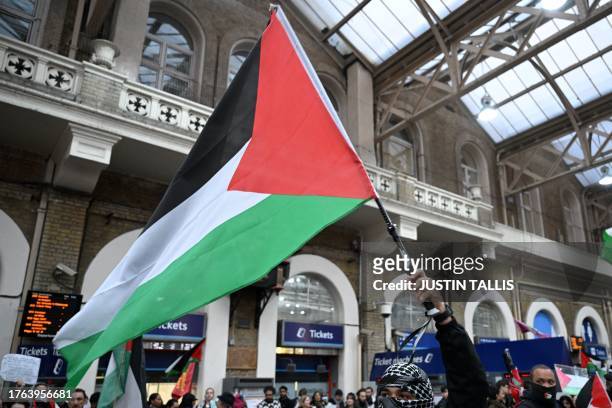 Protester waves a Palestinian flag as people take part in a sit-down protest inside Charing Cross station following the 'London Rally For Palestine'...