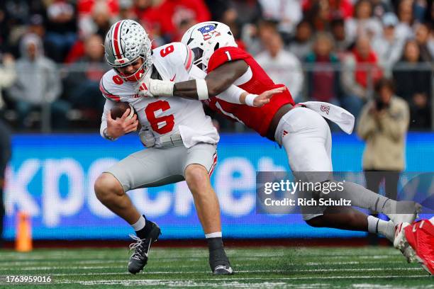 Quarterback Kyle McCord of the Ohio State Buckeyes is sacked by linebacker Mohamed Toure of the Rutgers Scarlet Knights during the first quarter of a...