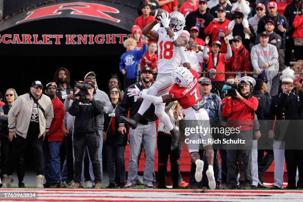 Wide receiver Marvin Harrison Jr. #18 of the Ohio State Buckeyes jumps over defensive back Robert Longerbeam of the Rutgers Scarlet Knights to make a...