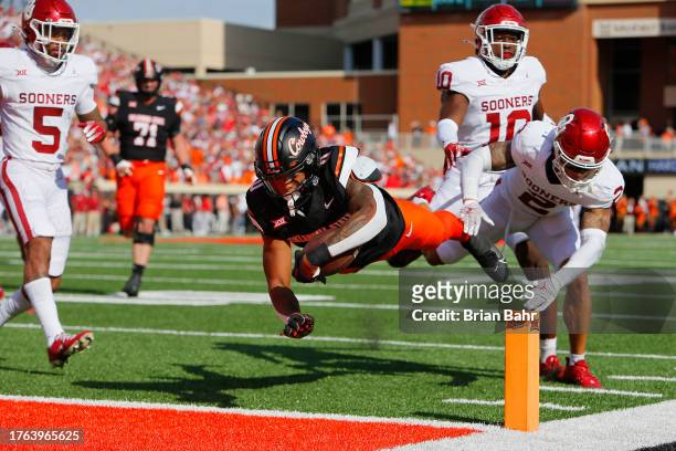 Running back Ollie Gordon II of the Oklahoma State Cowboys dives into the end zone on a 20-yard touchdown run against defensive back Billy Bowman Jr....
