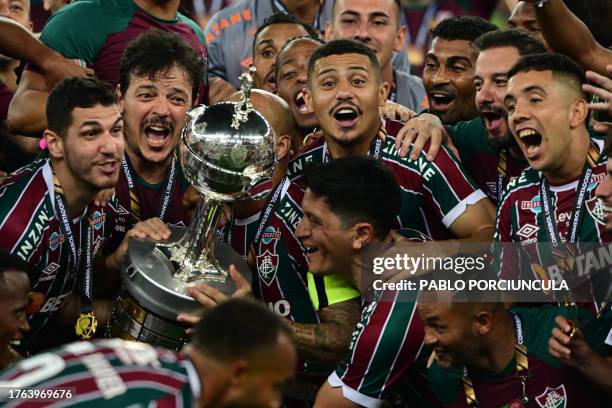 Fluminense's defender Nino , Fluminense's coach Fernando Diniz , Fluminense's midfielder Andre Trindade and teammates raise the trophy after winning...