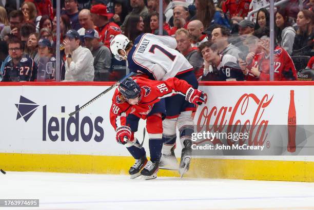 Rasmus Sandin of the Washington Capitals finishes a check on Sean Kuraly of the Columbus Blue Jackets during a game at Capital One Arena on November...