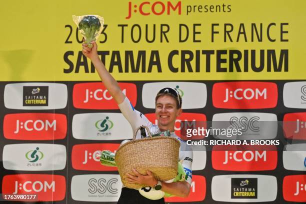 Team Emirates team member Tadej Poga?ar of Slovenia jokingly holds up a broccoli included in a basket of local produce presented to him on the podium...