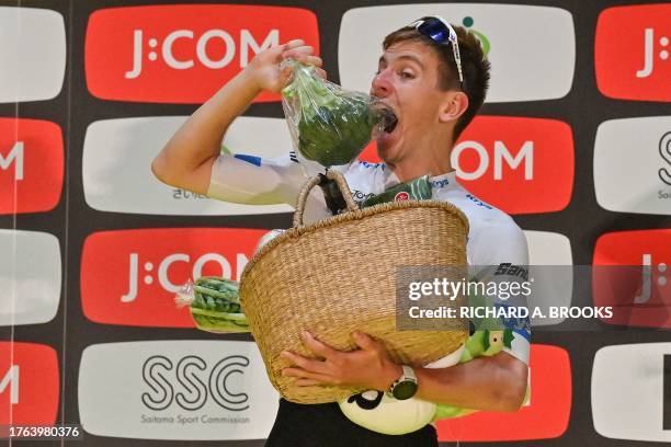 Team Emirates team member Tadej Poga?ar of Slovenia jokingly bites a broccoli included in a basket of local produce presented to him on the podium...