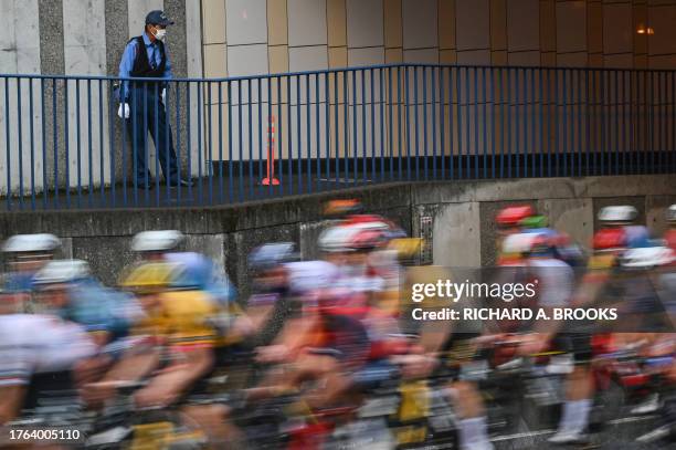 Member of security looks on as the peloton passes by during the Tour de France Saitama Criterium cycling race in Saitama on November 5, 2023.