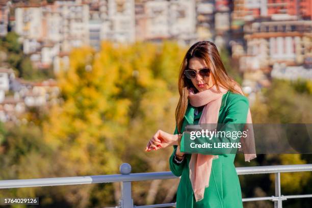 a young woman looks at her watch on her wrist - lerexis stockfoto's en -beelden