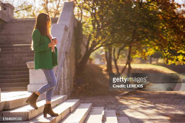 young woman walking down the stairs of a building in a city park - lerexis stockfoto's en -beelden