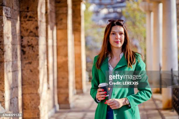 portrait of a young woman holding a paper coffee cup - lerexis stockfoto's en -beelden