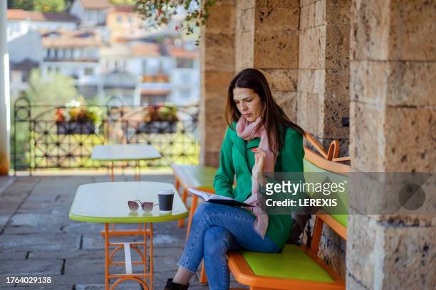 woman reading a book in the cafe - lerexis stockfoto's en -beelden