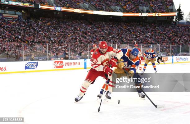 MacKenzie Weegar of the Calgary Flames and Warren Foegele of the Edmonton Oilers vie for the puck during the first period of the 2023 Tim Hortons NHL...