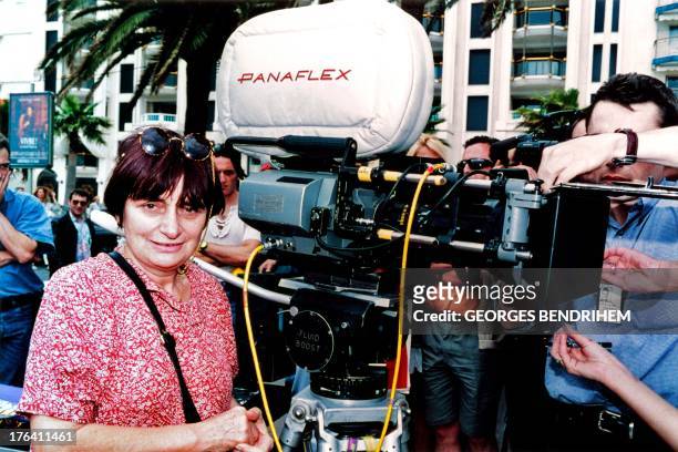 French director Agnes Varda gives instructions to actorsnext to a camera in Cannes on May 13, 1994 during the shooting of her next movie "Mes cent et...