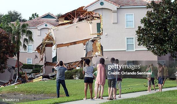 People take pictures Monday, August 12, 2013 after a sinkhole swallowed two building at Summer Bay Resort in Orlando, Florida late Sunday night.