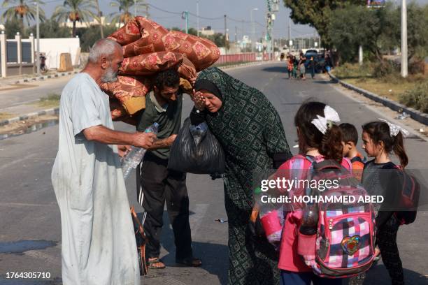 Woman washes her face as people carrying some of their belongings reach the central Gaza Strip on foot via the Salah al-Din road on their way to the...