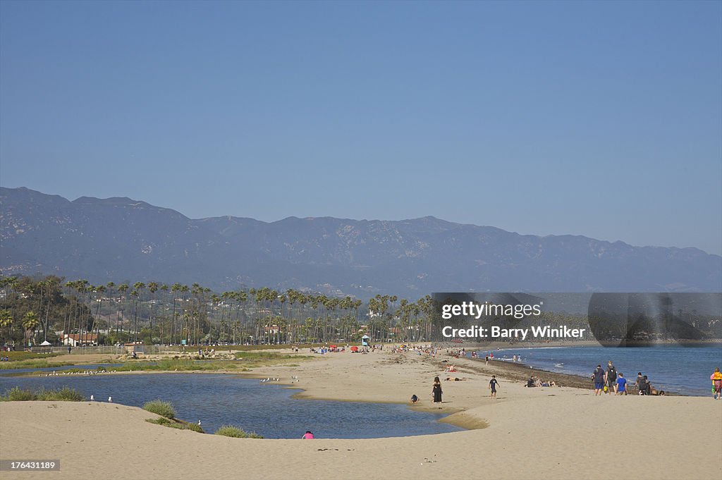 People strolling on white sand near blue water.