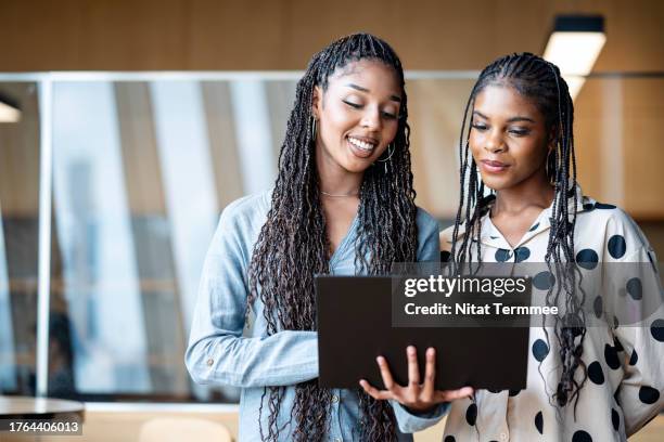 encourage cross-functional collaboration to drive projects success. front view of an african-american project leader having discussion with her team to review a project plan on a laptop computer in a tech business office. - personalized photos et images de collection