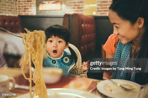 family sharing spaghetti in a restaurant - chinese restaurant photos et images de collection