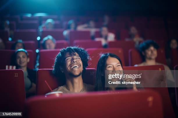 fröhliches vielfältiges paar, das einen film im kino genießt. - filmindustrie stock-fotos und bilder