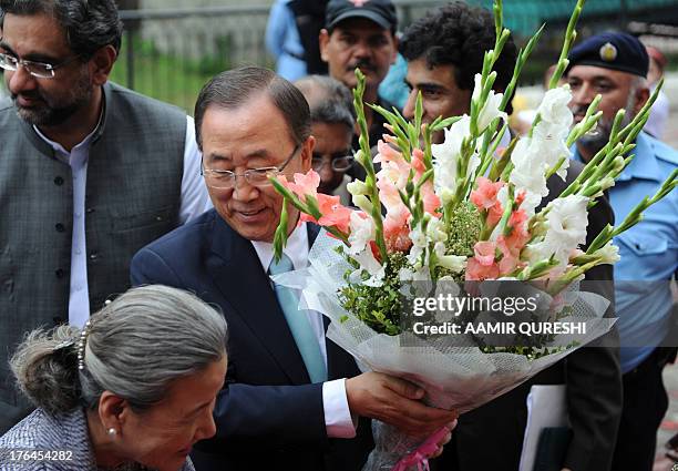 Secretary-General Ban Ki-moon holds up flowers upon his arrival at the Islamabad College for Girls in Islamabad on August 13, 2013. UN chief Ban...