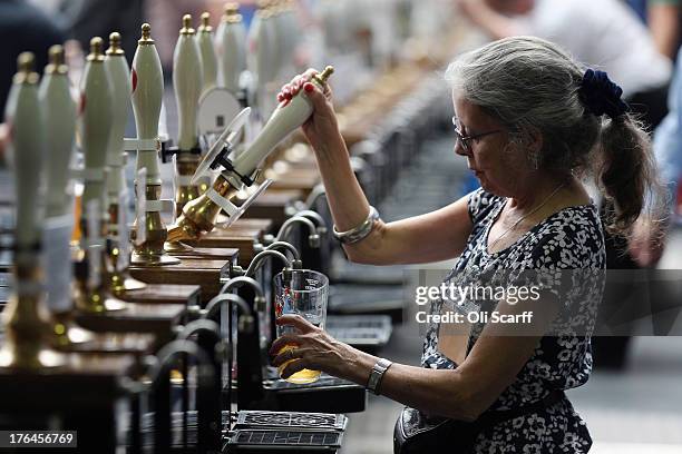 Woman pulls a pint of beer behind a bar in the Great British Beer Festival in the Olympia exhibition centre on August 13, 2013 in London, England....