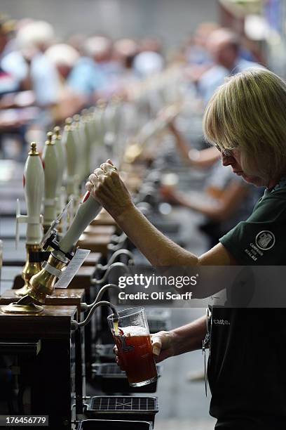 Woman pulls a pint of beer behind a bar in the Great British Beer Festival in the Olympia exhibition centre on August 13, 2013 in London, England....