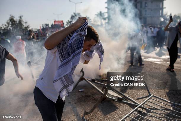 Protestors take cover from the tear gas fired by Turkish anti-riot police during a Pro-Palestinian demonstration against US secretary of state's...