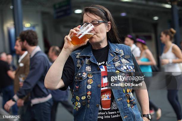 Lynne Morgan, wearing a denim jacket decorated with beer-related pin badges, enjoys a pint of beer at the Great British Beer Festival in the Olympia...