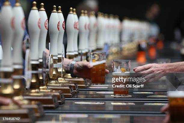 Man collects his drink at a bar in the Great British Beer Festival in the Olympia exhibition centre on August 13, 2013 in London, England. The...