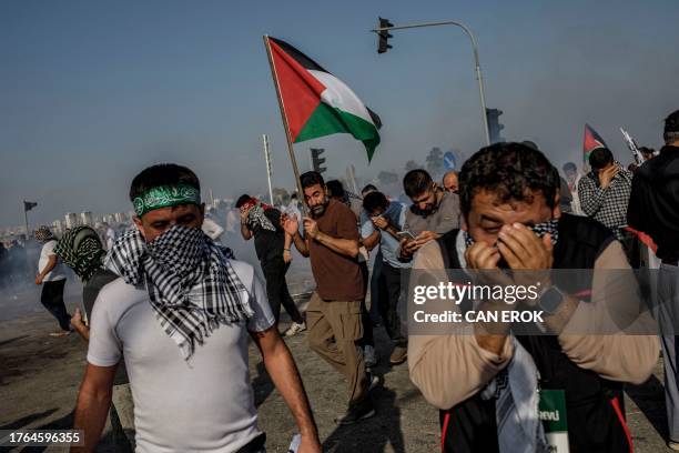 Protestors cover their faces to protect from the tear gas fired by Turkish anti-riot police during a Pro-Palestinian demonstration against US...