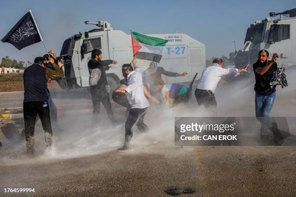Protestors hold a Palestinian flag as Turkish anti-riot police uses water cannons to disperse them during a Pro-Palestinian demonstration against US...