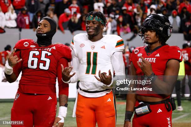 Jacarrius Peak and MJ Morris of the NC State Wolfpack pose for a photo with Jacurri Brown of the Miami Hurricanes following their game at...