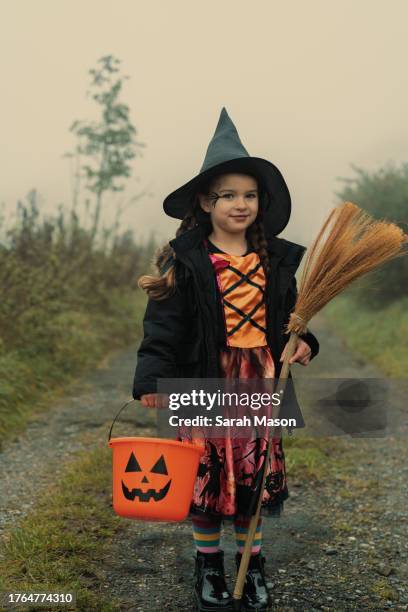 little girl in witch costume smiling ready for trick or treating - sarah green stock pictures, royalty-free photos & images